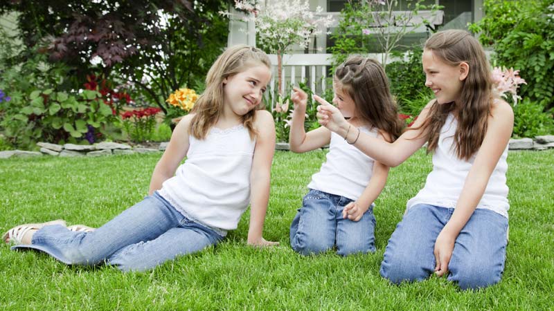 Três meninas sentadas na relva falam sobre a menarca, ou primeira menstruação